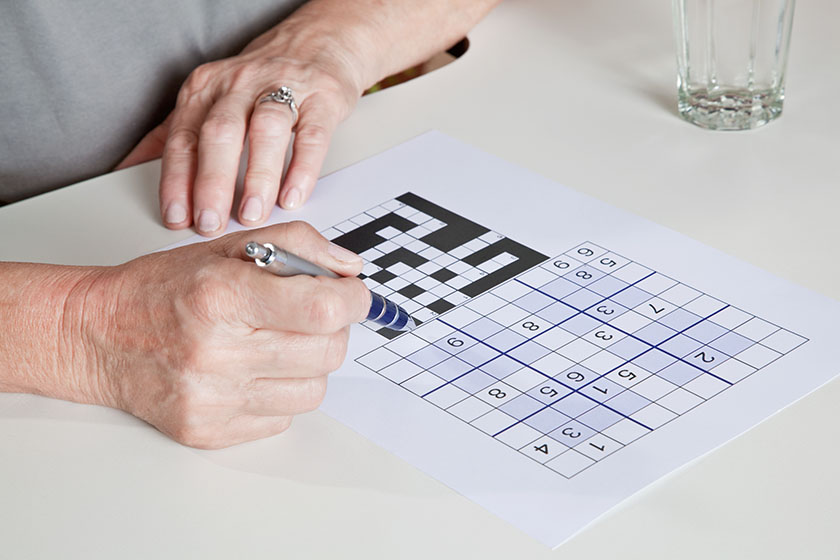Portrait of mature woman playing a mind game sudoku puzzle.