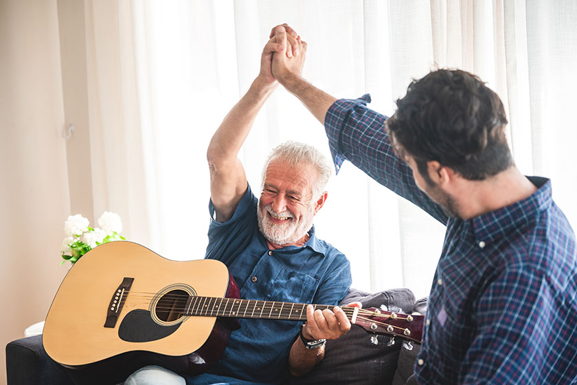 elderly dad and son are playing music as a mind game at home, relax activity at home with family