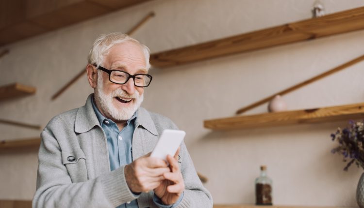 A senior is curiously looking at his iPhone.