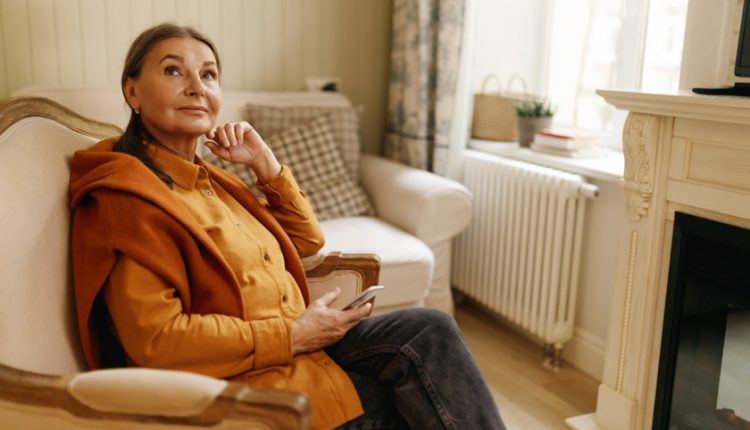 Senior woman in winter clothes and cardigan sitting in an armchair