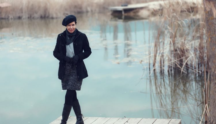 Mature woman standing outside on with a lake behind her