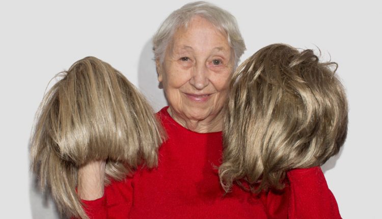 Smiling senior woman holding up two wigs