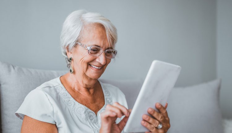 senior woman smiling and reading on his tablet