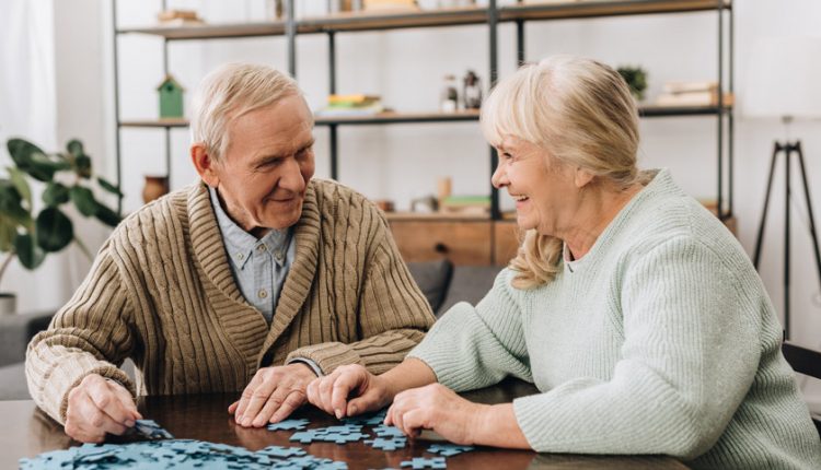 happy senior couple solving a jigsaw puzzle
