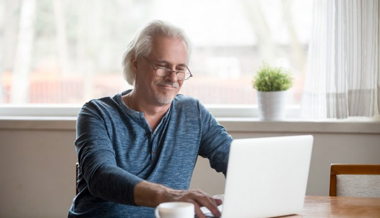 Senior man searching for jobs on his laptop