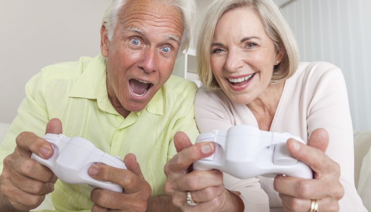 Senior couple playing with controllers and laughing