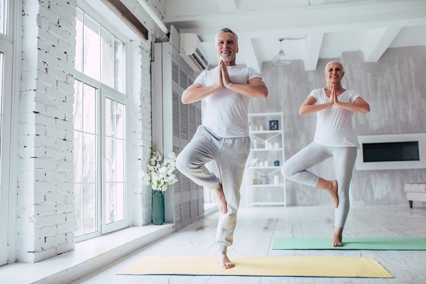 Senior couple is doing fitness training at home. Doing yoga together. 