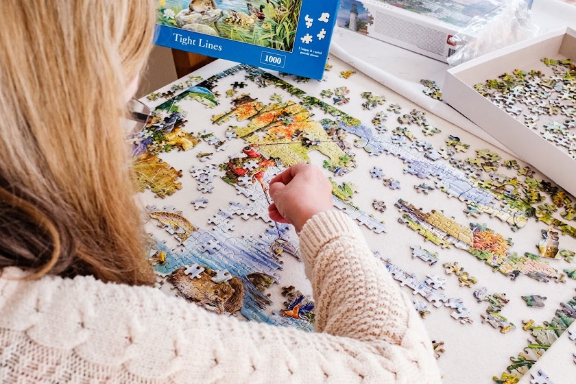 Lady doing a jigsaw puzzle of 1,000 pieces.