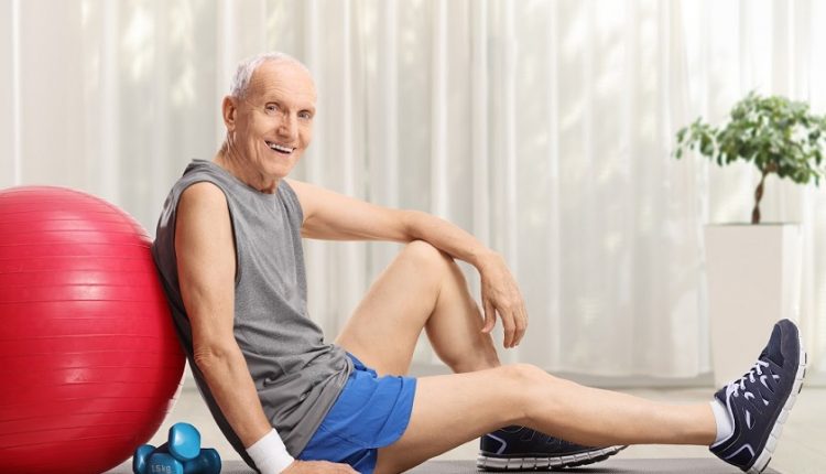 Elderly man with fitness ball and dumbbells sitting on an exercise mat at home, Exercises to Reduce Dementia Risk