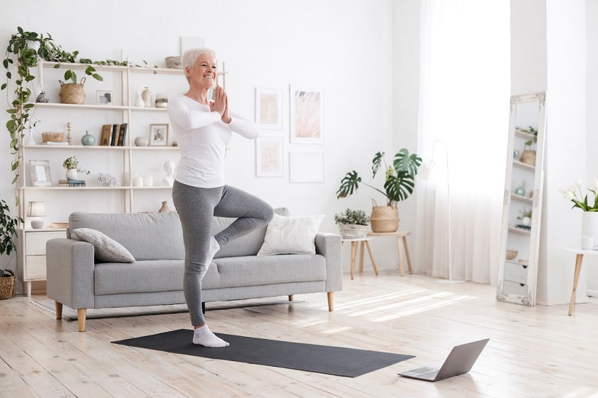 Sporty Senior Woman Practicing Yoga At Home, Standing In Tree Pose.