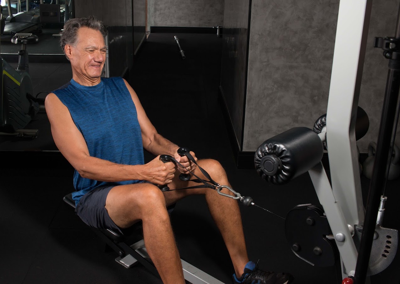 Senior Man working out on a rowing machine in the gym