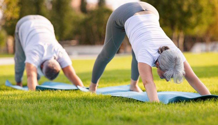 Senior man and woman doing exercises to get rid of text neck on their mats in a park