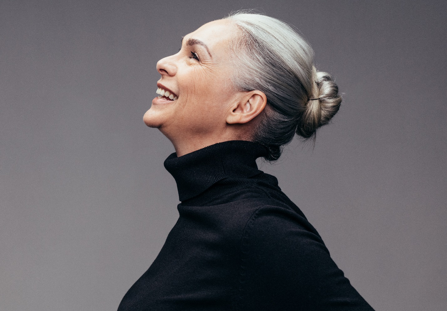 Side profile of an attractive senior woman with tied grey hair