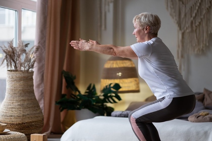 Senior caucasian woman practicing advanced yoga Chair Pose or Utkatasana at home