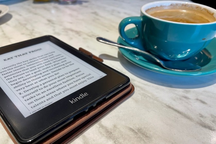 Amazon Kindle Paper White on a table with a cup of coffee
