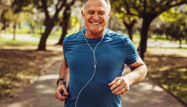 Happy and healthy senior man jogging with earphones in his ears