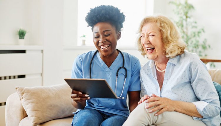 Senior woman and a nurse laughing happily