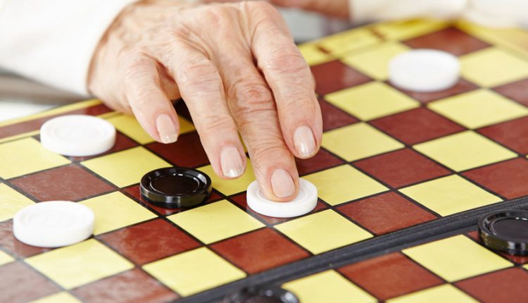 hands of a senior woman playing checkers