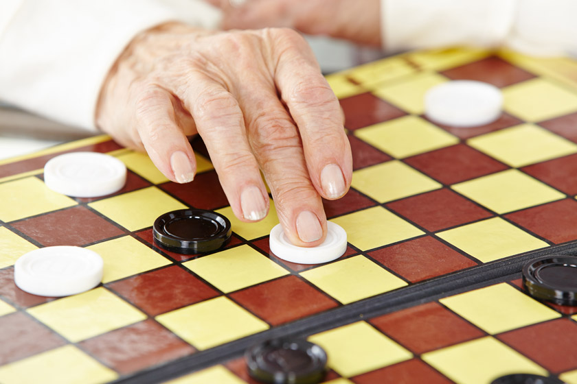 hands of a senior woman playing checkers