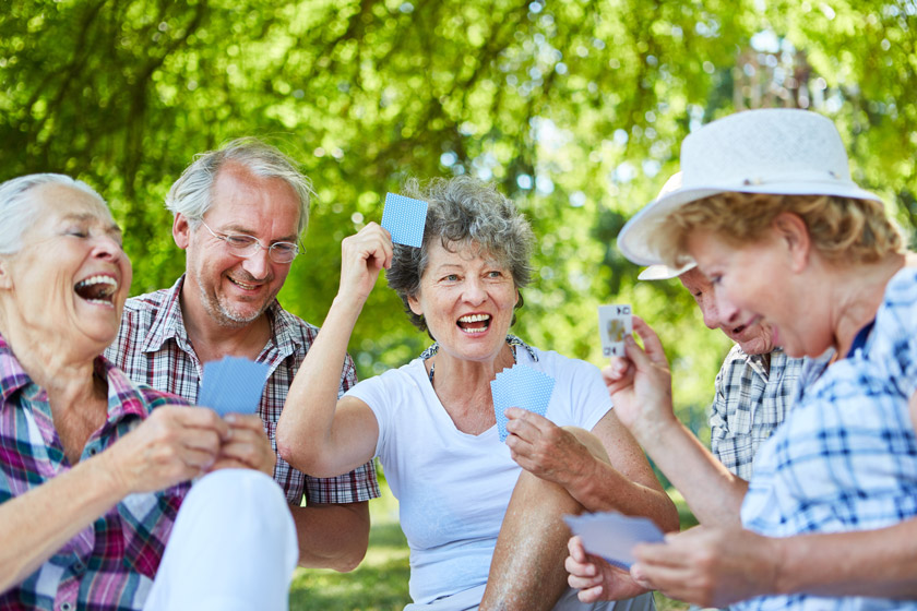 A happy group of seniors playing a card game in a park