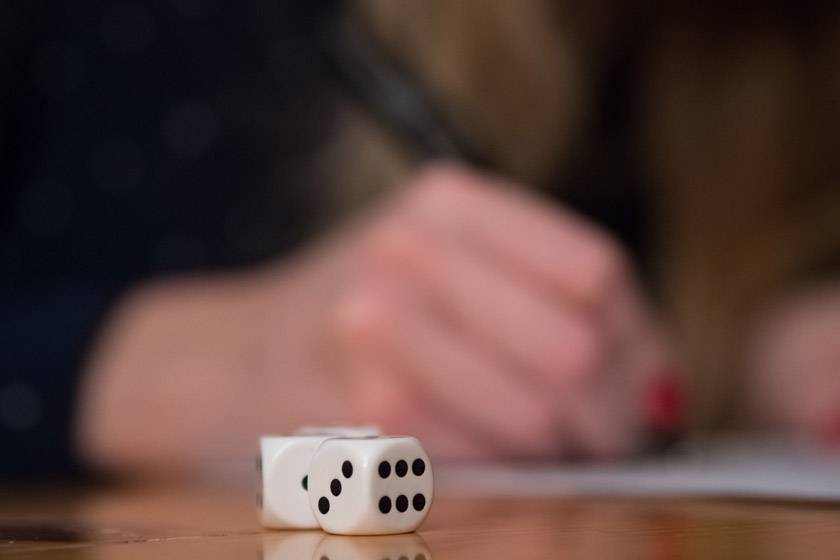 The close-up view of a dice on a table in front of a woman