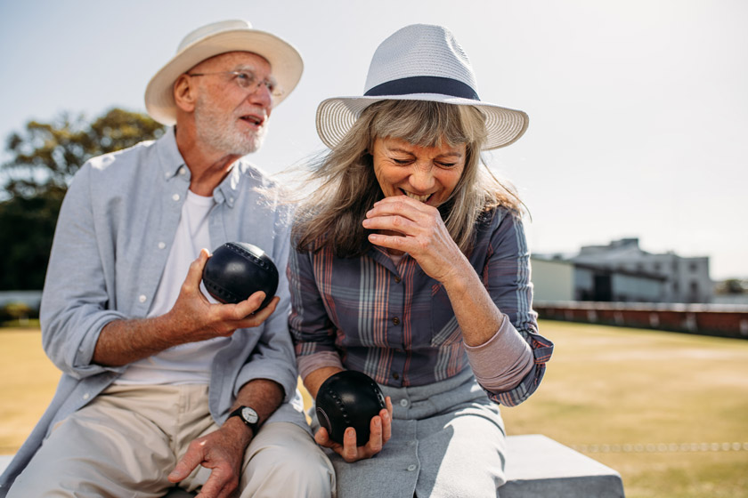 Senior couple laughing while holding balls for a game