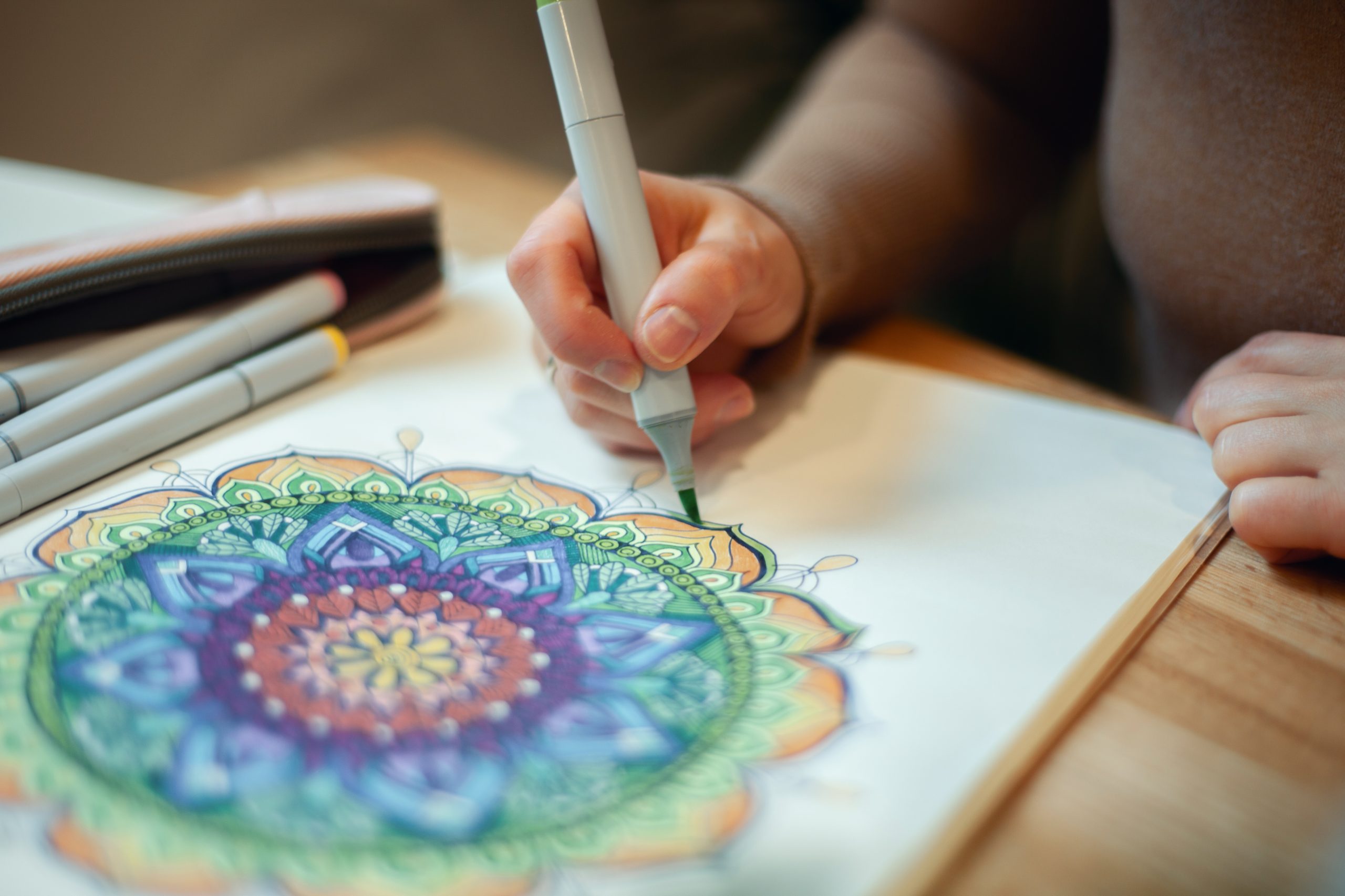 colouring for dementia, Woman holding a green marker and colouring a mandala pattern