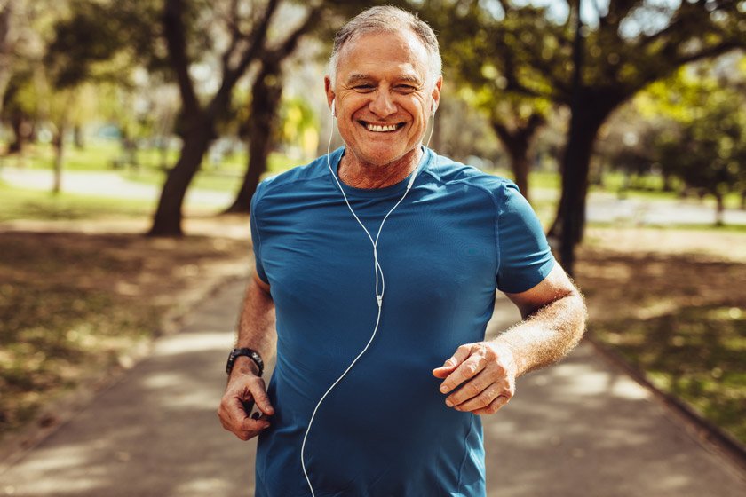 Happy and healthy senior man jogging with earphones in his ears