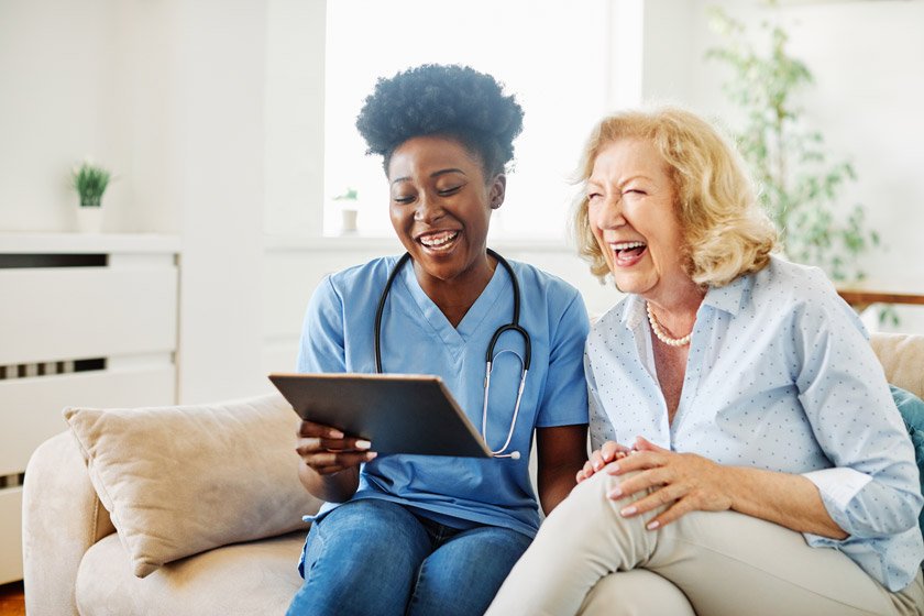 Senior woman and a nurse laughing happily
