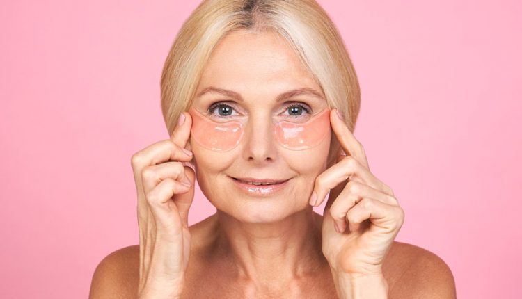 Beautiful senior woman using eye patches for her skin routine