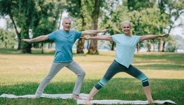Happy mature couple doing yoga exercises in the park