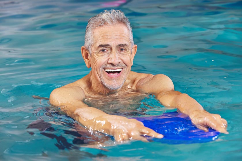 Happy senior man doing aqua yoga in the pool
