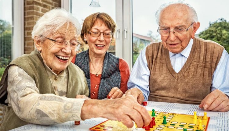 games to play with dementia patients, games to play with the elderly with dementia, Three seniors, one male, two females, playing a board game happily