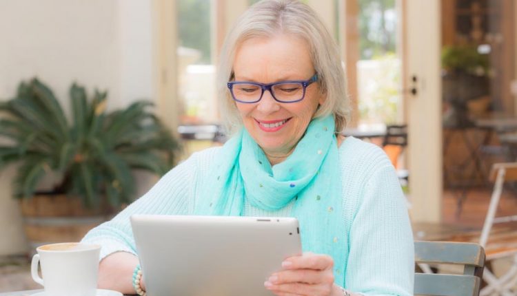 Beautiful senior woman sitting in a cafe playing with his iPad