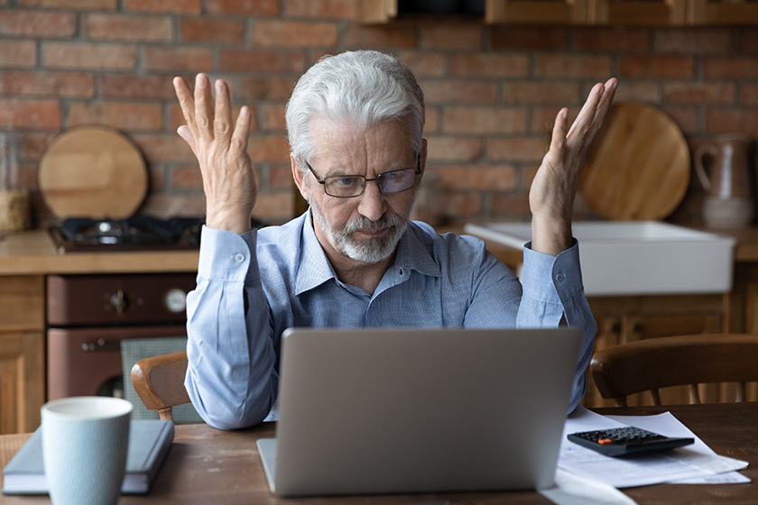 A senior man sitting in front of his laptop, frustrated because of his financial situation