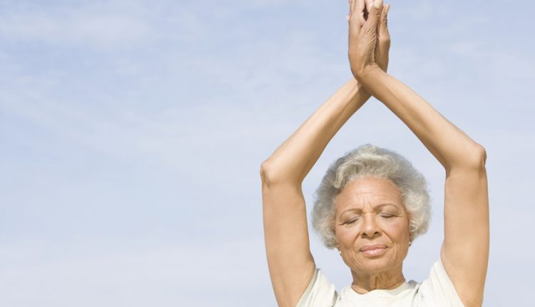 Senior woman doing a yoga pose and smiling to improve her mental health