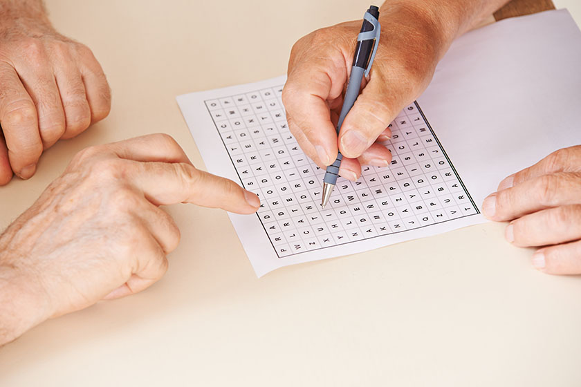 Hands of two senior people solving a word search quiz together