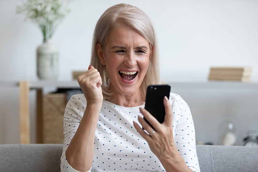 Overjoyed mature older woman holding her phone, happy because she won a word game