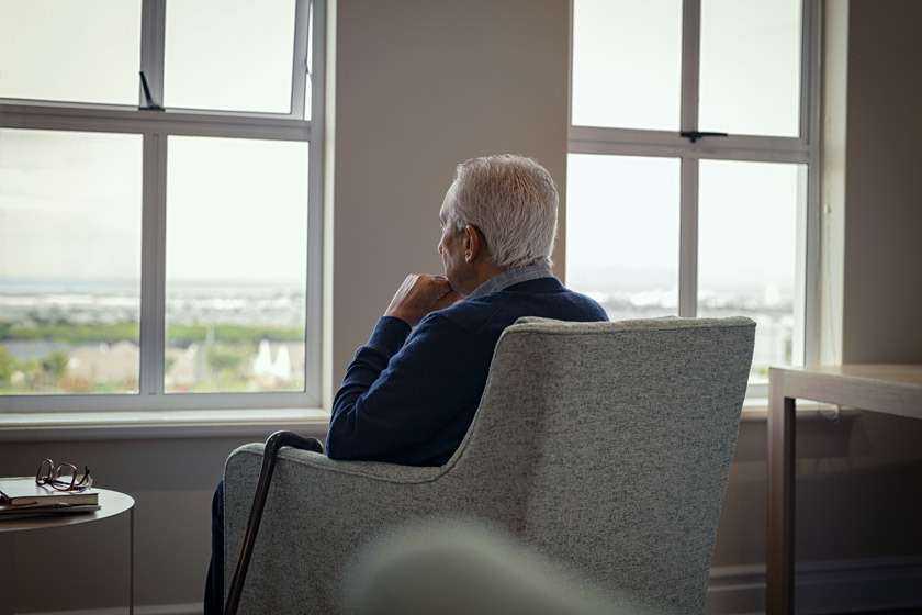 Depressed senior man looking out the window