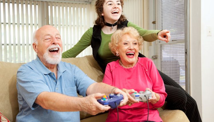 Senior couple playing a video games with their granddaughter and having fun