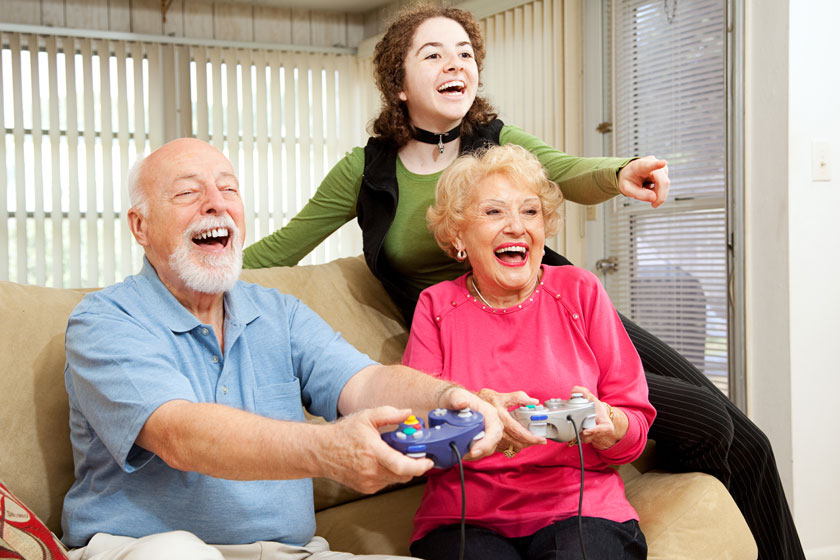 Senior couple playing a video games with their granddaughter and having fun