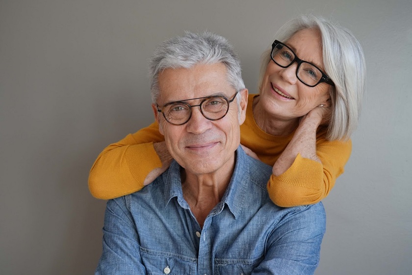 Portrait of relaxed fun senior couple wearing glasses on background