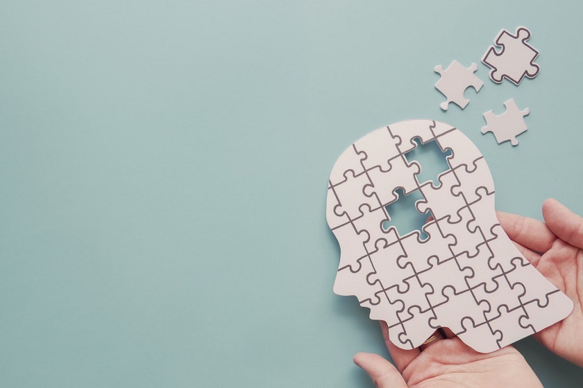 Hands holding brain with puzzle paper cutout representing mild dementia