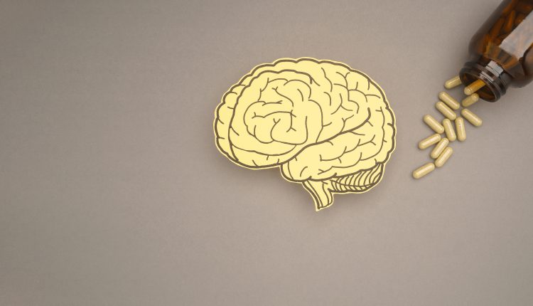 Cutout of a human brain next to a bottle of pills
