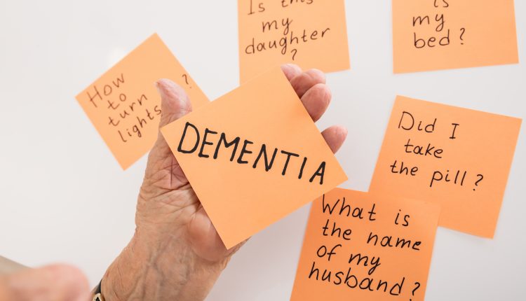 Hand of a senior holding a stick note reading dementia