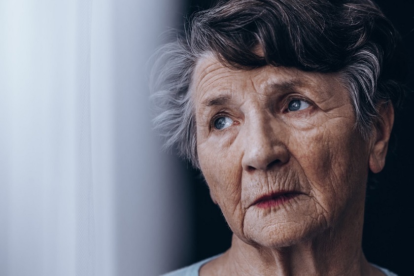 Depressed senior woman looking out of the window
