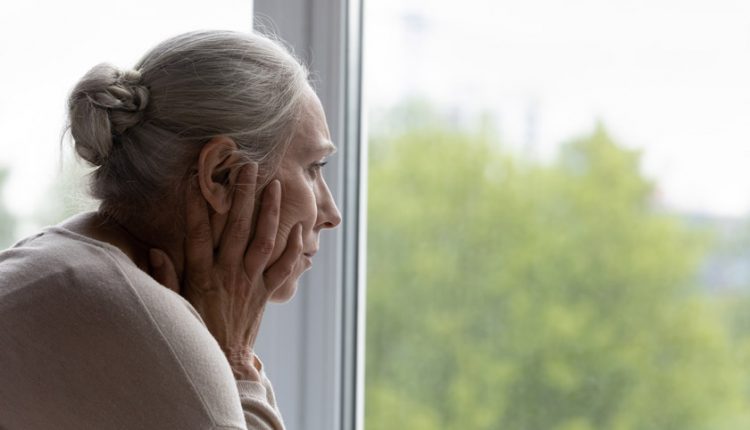 Depressed senior lady looking out the window