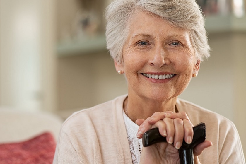 Normal Ageing: Senior woman holding onto her cane, smiling at the camera