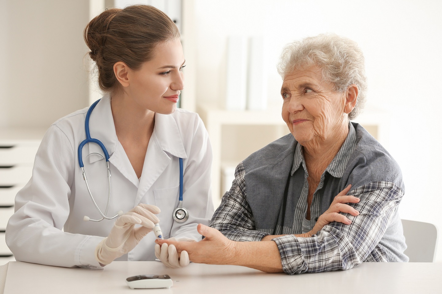 Doctor measuring blood sugar level of diabetic patient in clinic, diabetes and Alzheimer's