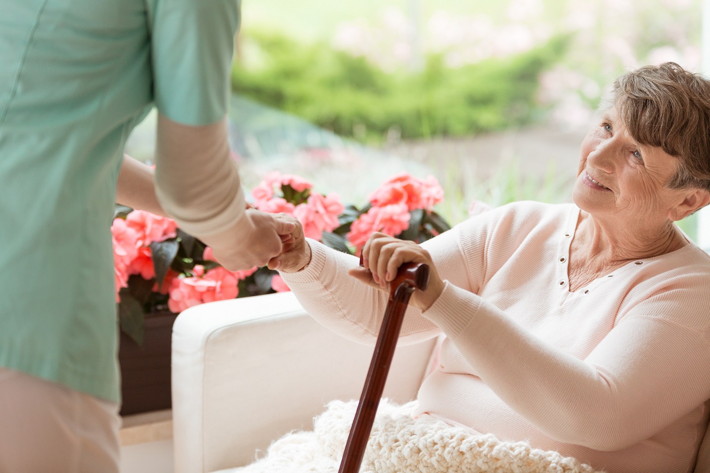 Parkinson's and Alzheimer's, Doctor helping an elderly woman with Parkinson's disease get up from a sofa in a rehabilitation facility